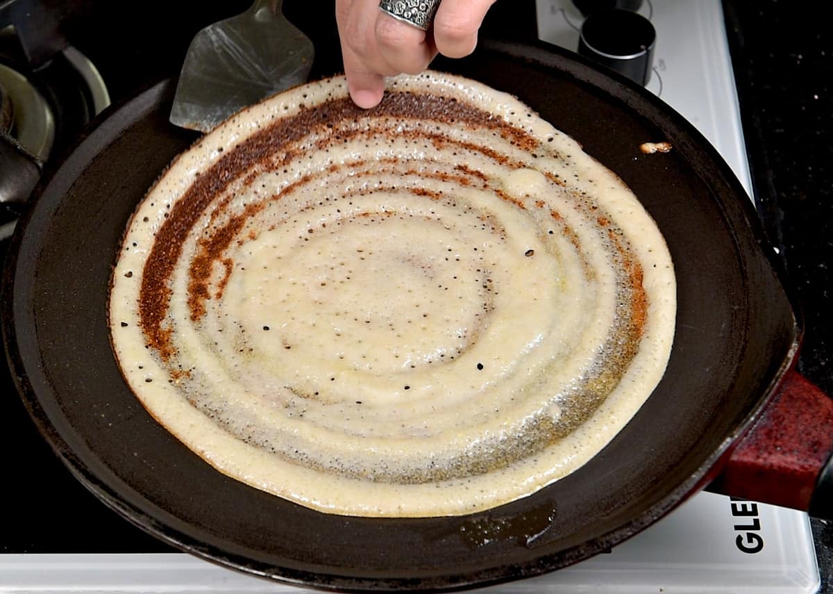 A perfectly cooked dosa leaving the edges of the griddle.