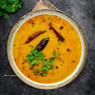 Close-up view of Rajasthani yellow dal lentils stew served in earthen bowl.