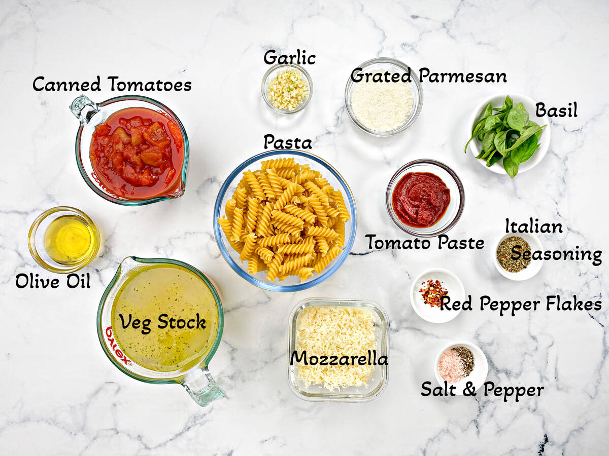 Recipe ingredients each in individual bowls: Cheeses, canned tomatoes and paste, seasonings, herbs and olive oil.