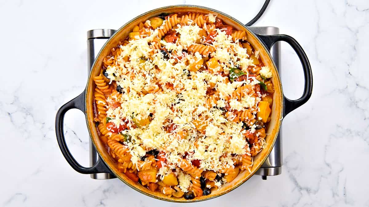 Shredded mozzarella topped over cooked pasta in the pot.