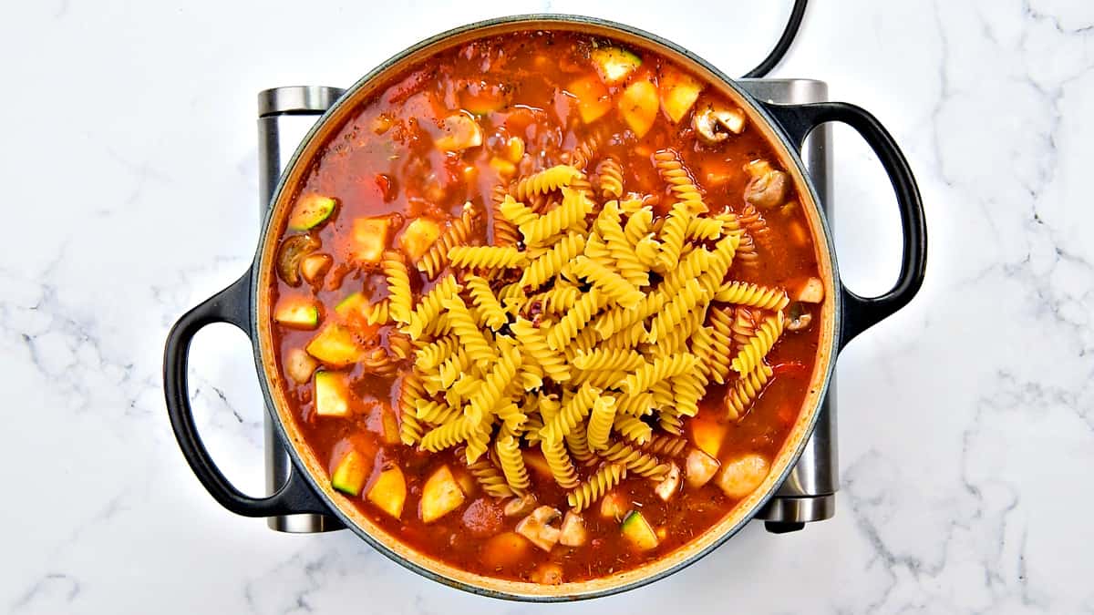 Pasta added to the vegetable stock in the pot.