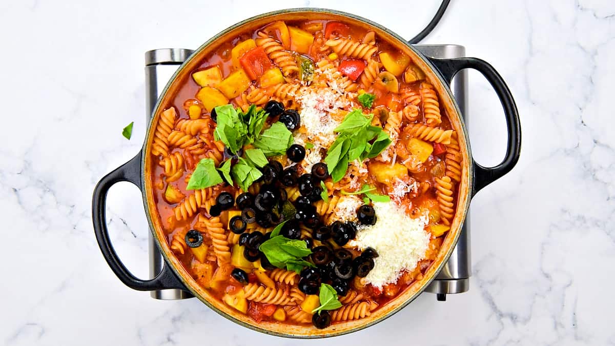 grated parmesan, sliced olive and roughly torn basil to cooked pasta in pot.