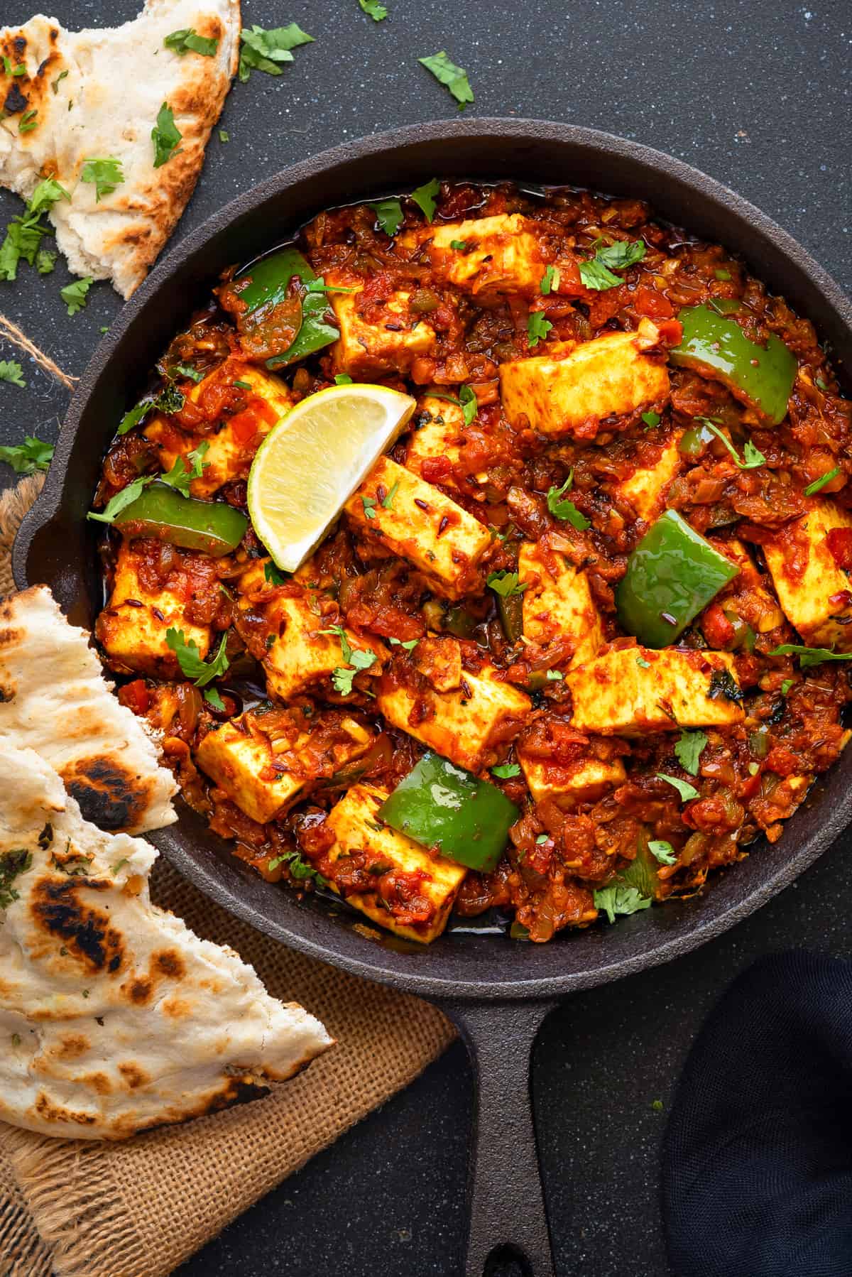 Close-up view of iron skillet with paneer tawa masala.