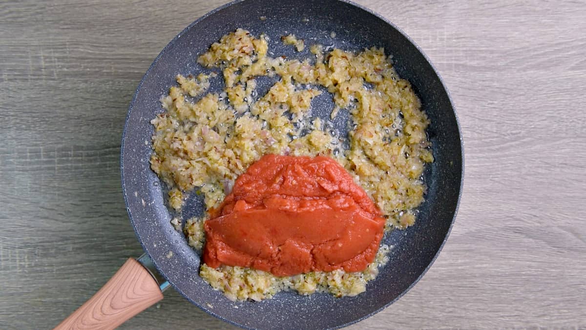 Grated tomatoes added to skillet with sautéed onion mixture.