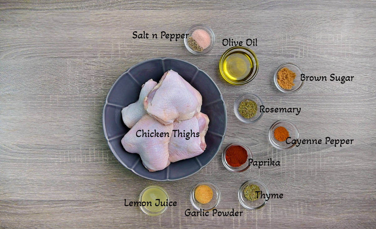 Recipe ingredients you need: A gray bowl with 4 raw skin-on chicken thighs, individual glass bowls with spices, olive oil, and lemon juice.