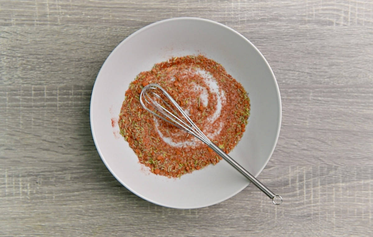 Spices and a whisk in a white bowl.