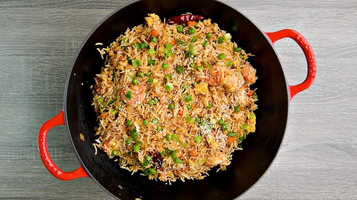 Wok with shrimp fried rice sprinkled with sesame seeds.