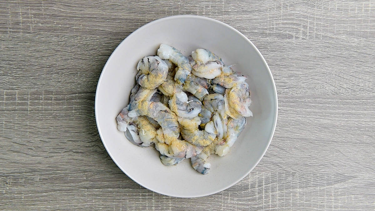 Raw shrimp and spices in a white bowl.