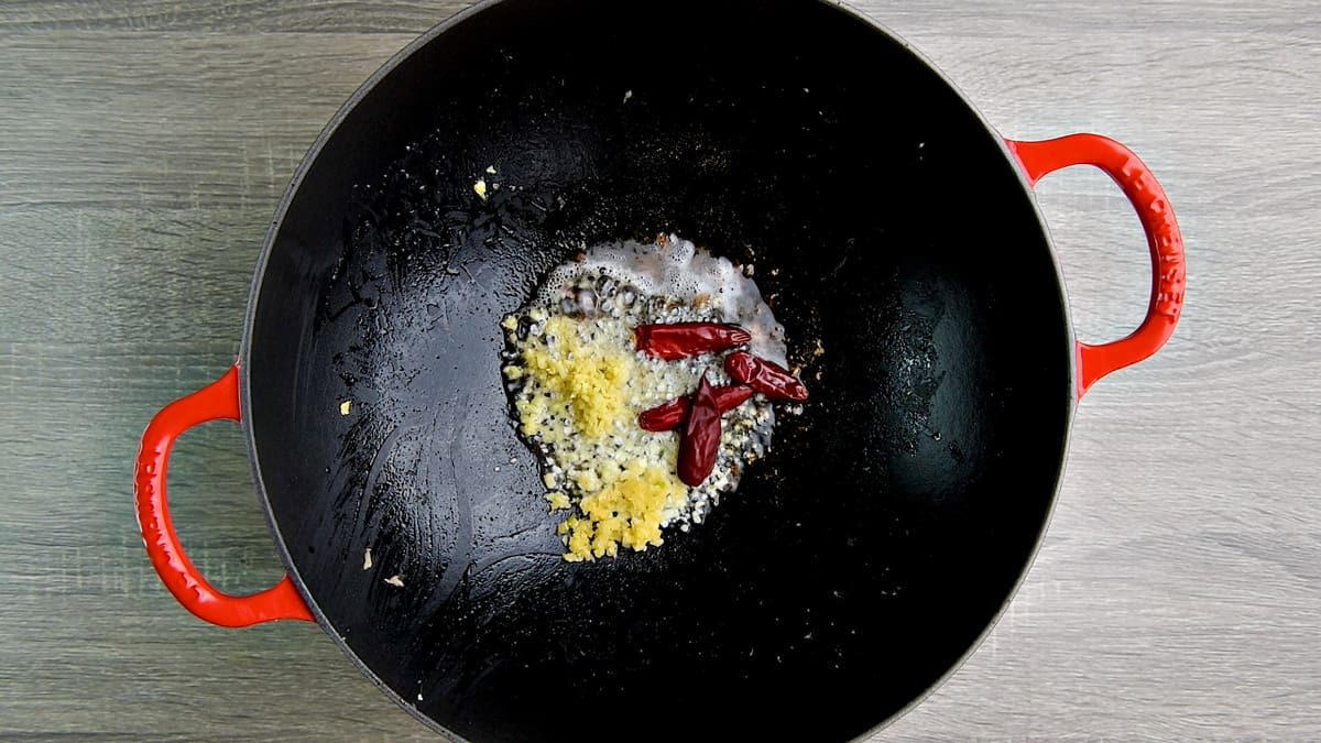 Stir frying garlic, ginger  and dry red chiles in a wok.