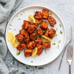 White plate with serving of salmon bites, with slices of lemon tucked in.