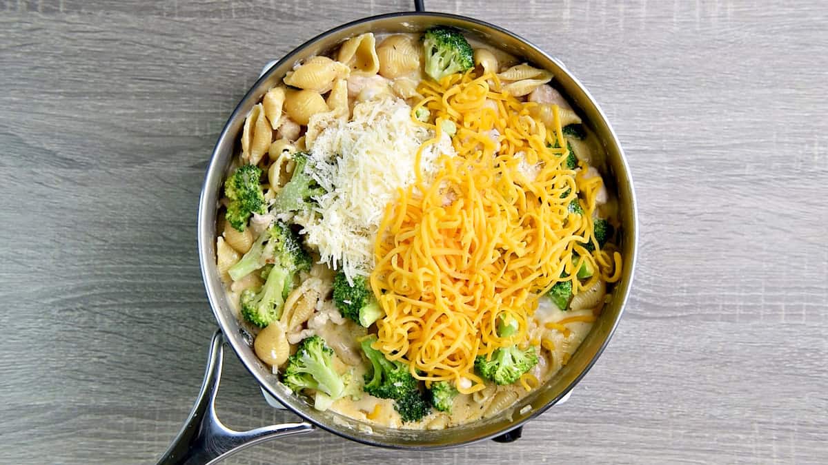 Adding shredded cheeses to the pot.
