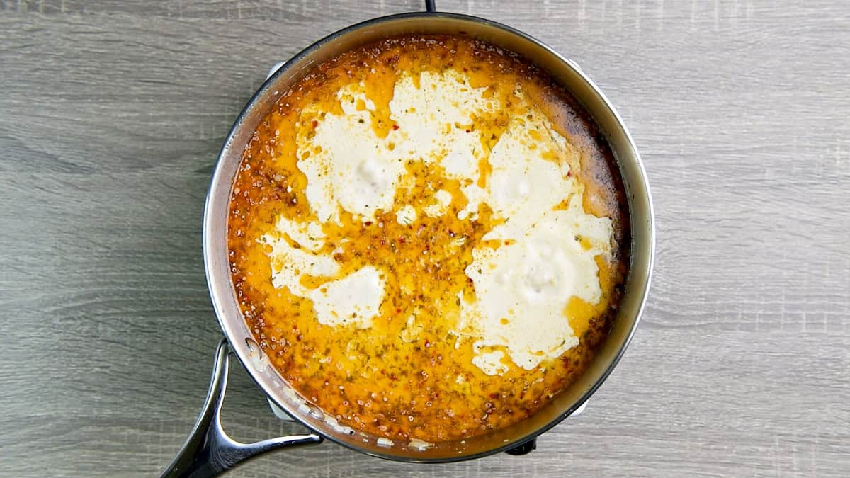 Skillet with broth and heavy cream.