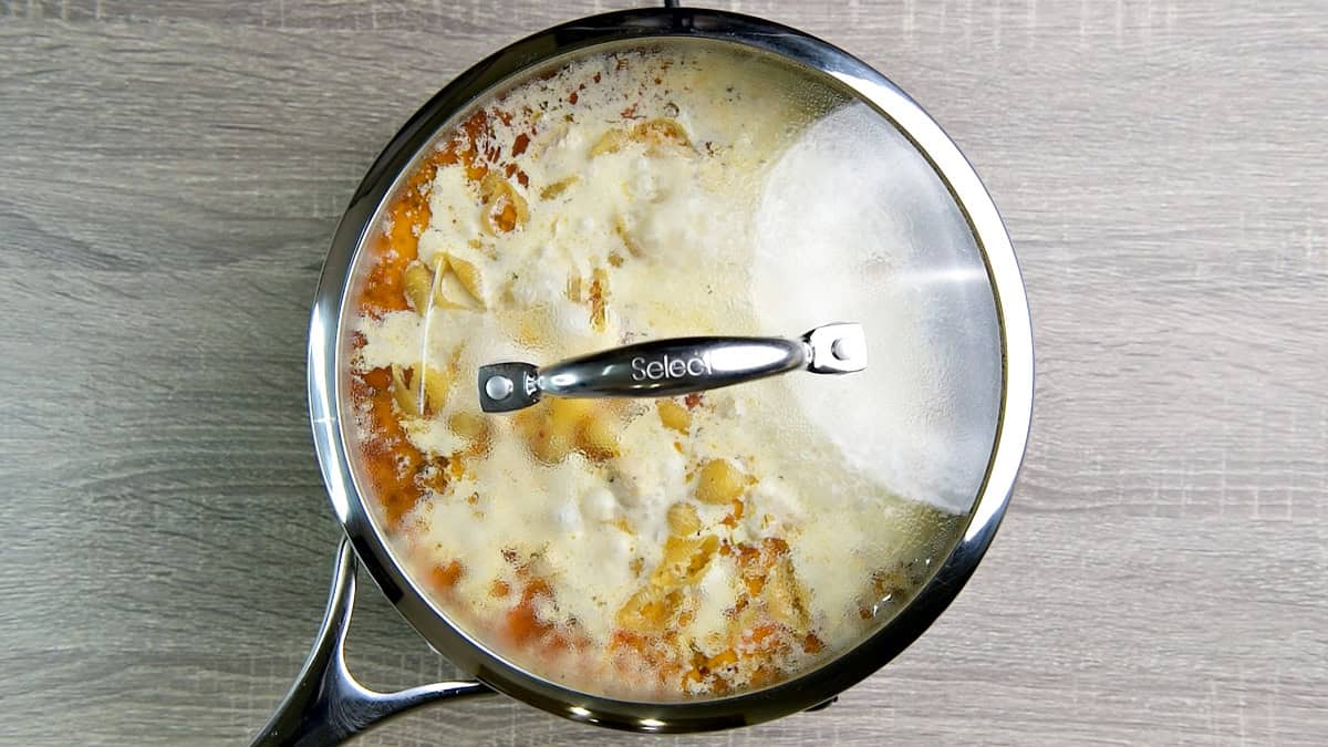 Covered skillet of pasta and sauce.