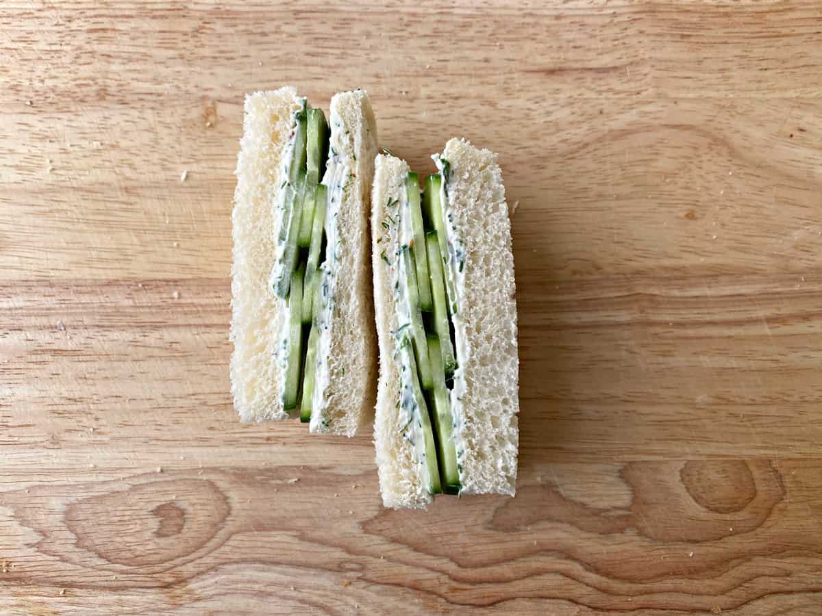 Two slices of cream cheese cucumber finger sandwiches, all on their sides to show the middles to camera.