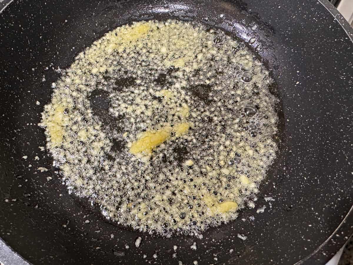 Minced garlic frying in hot oil in a skillet.