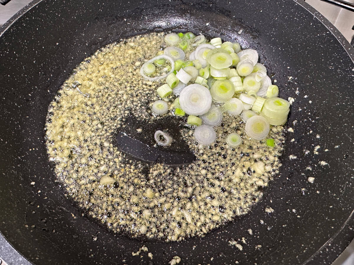 Add sliced scallion whites to the skillet.