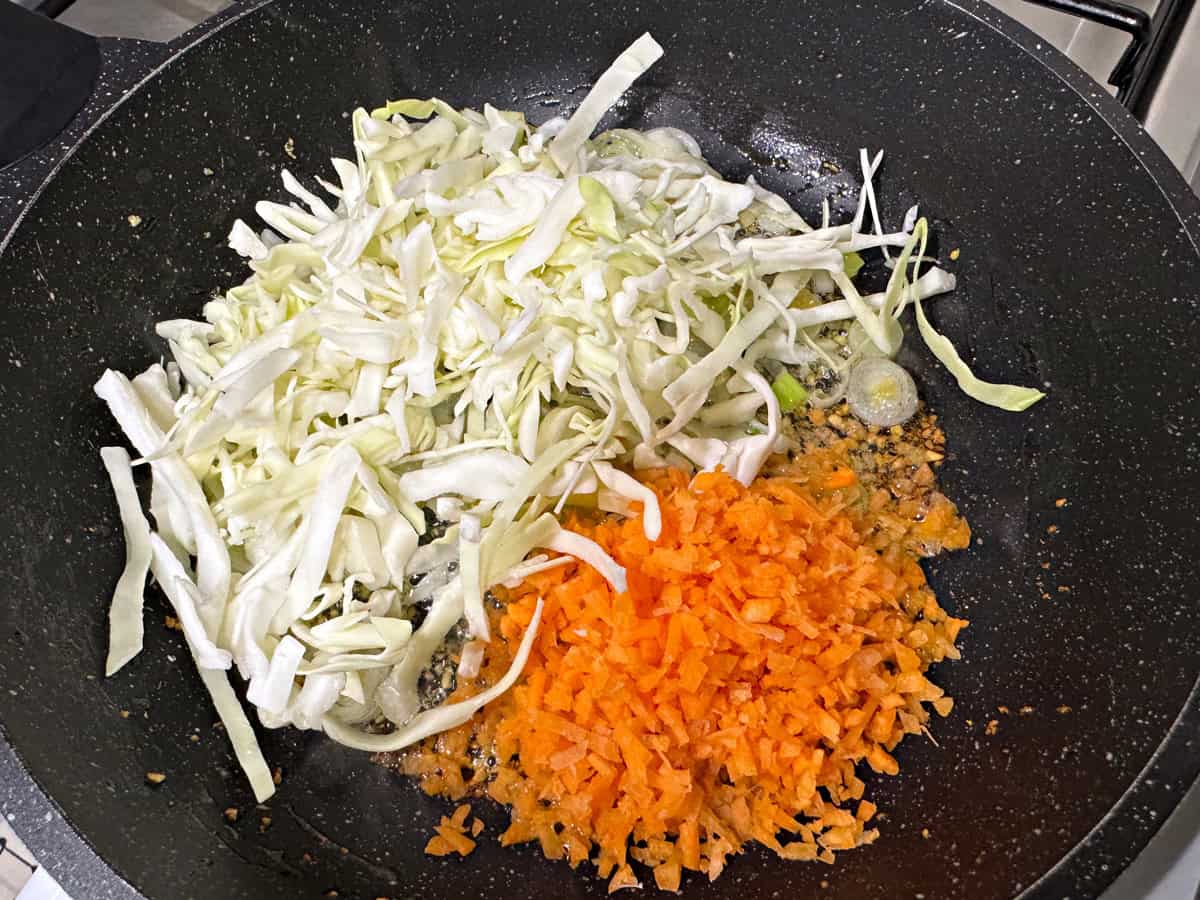 Add shredded cabbage and chopped carrot to the skillet.
