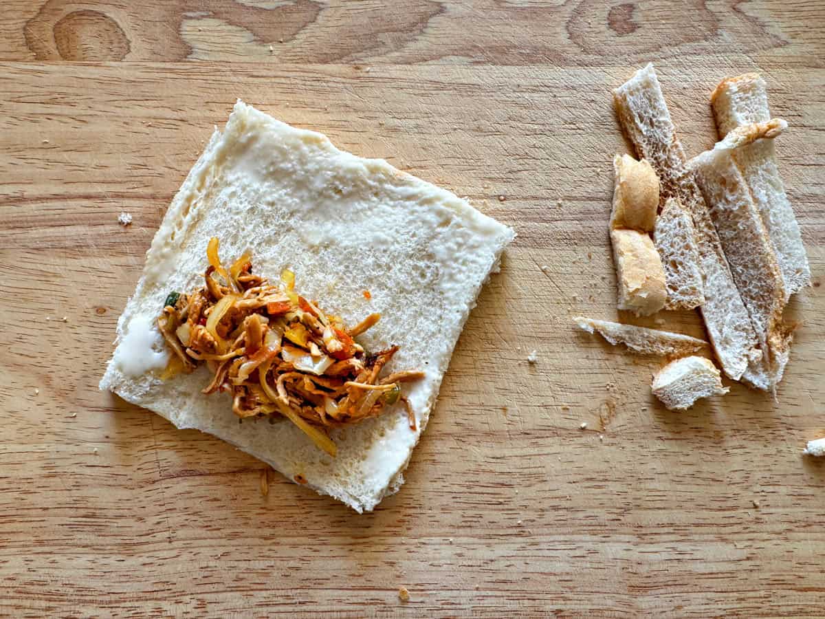 Place the prepared chicken filling on one side of the bread and appy flour slurry on all the sides.