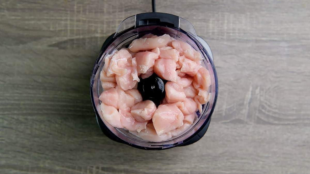 Boneless chicken cubes in a chopper.