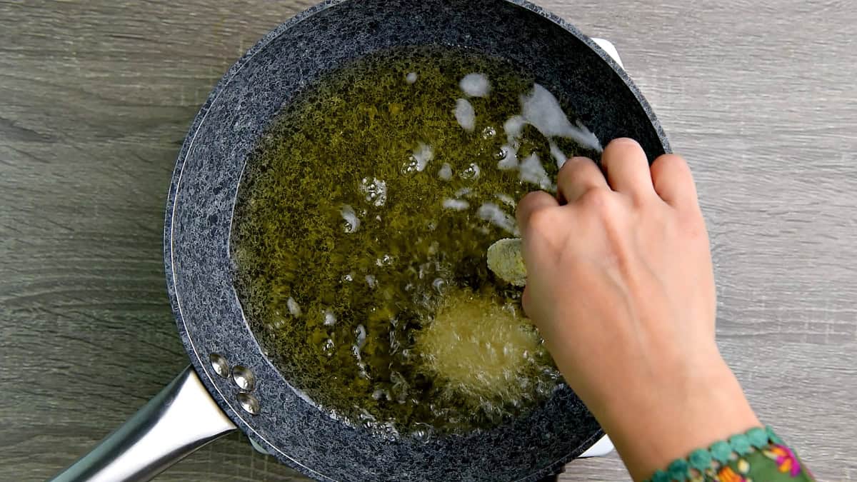 Adding nuggets to the hot oil in a wok.