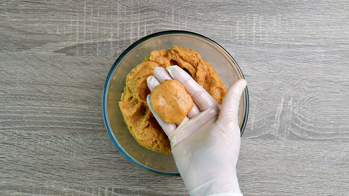 A gloved hand holding a raw nugget.