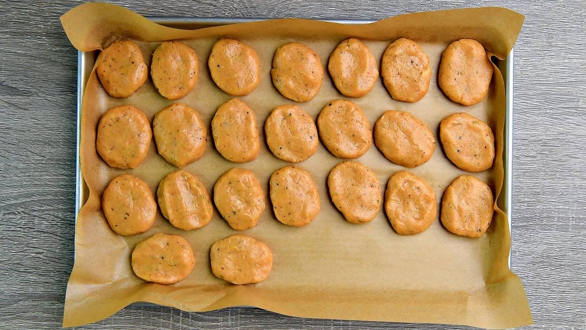 Raw chicken nuggets on a parchment lined sheet pan.