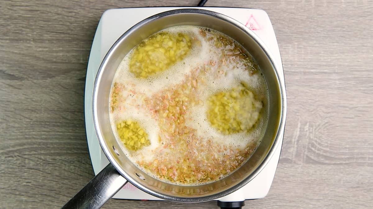 The sauce pan with water and ginger coming to a boil.