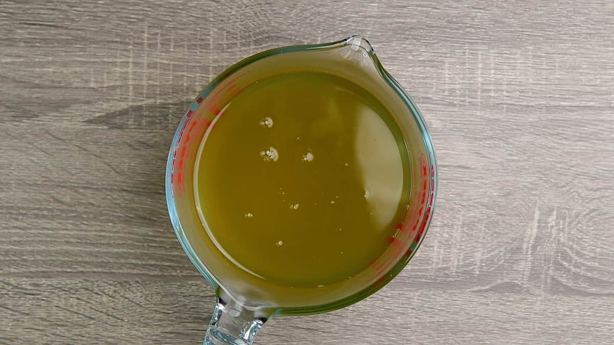 A measuring cup full of ginger simple syrup.