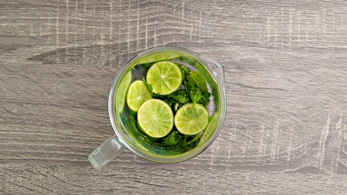 A pitcher full of muddled lime and mint leaves.