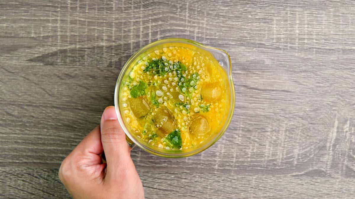 Mango mojito garnished with mint in a pitcher.