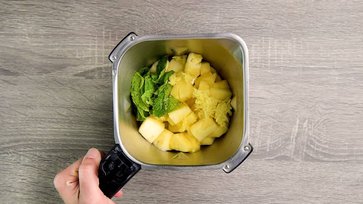 Blender full of pineapple chunks, ginger, lime juice, simple syrup and fresh mint leaves.