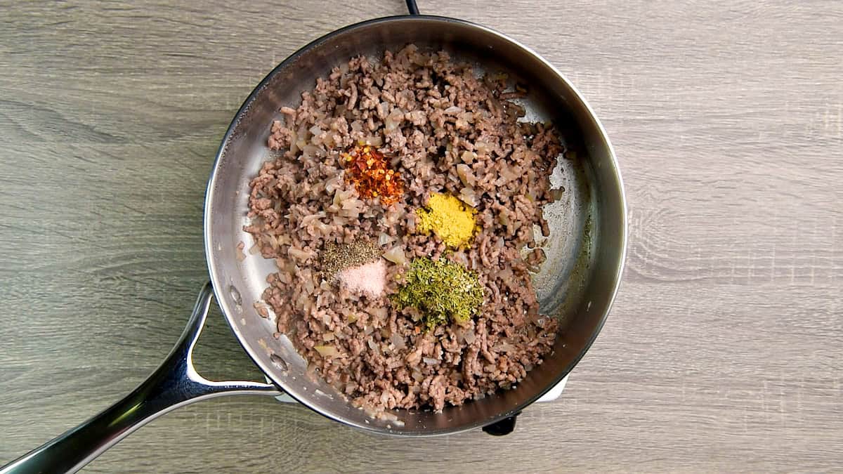 Dried thyme, mustard powder, red pepper flakes, salt, pepper followed by tomato paste added to the cooked ground beef.