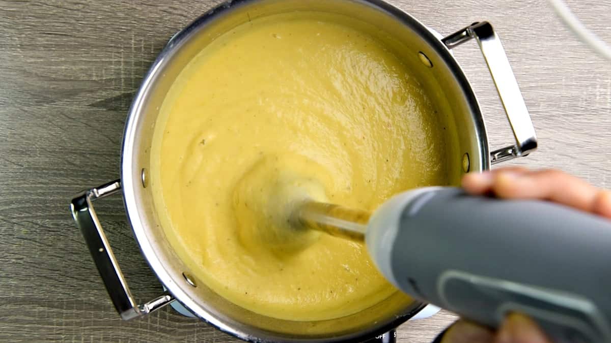 Blending the soup with immersion handheld blender to creamy and smooth.