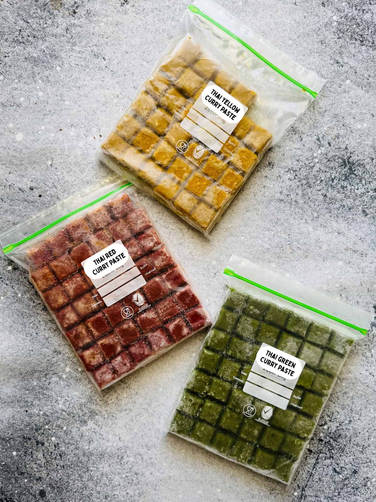 Top-down view of red, yellow, and green curry paste that has been cubed and frozen for ready to be used in recipes in the future.