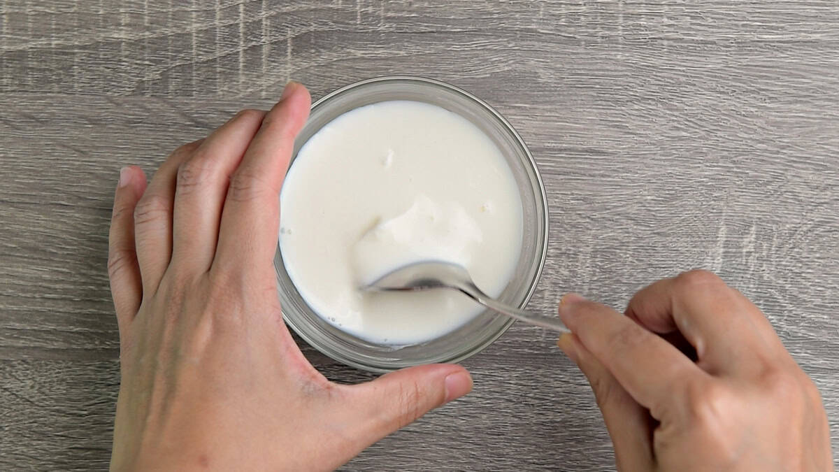 Sour cream starter is being mixed into a bowl that includes Greek yogurt, whole milk, and vinegar.