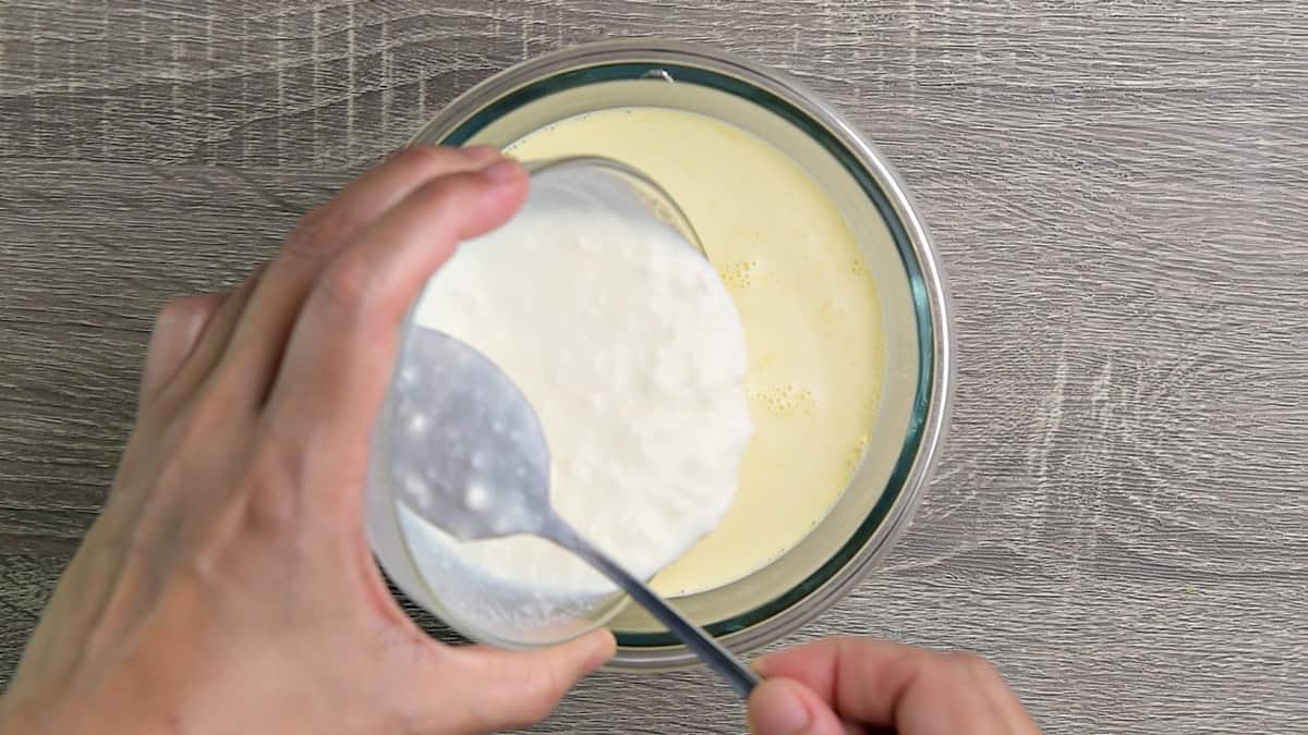 Top-down view of greek yogurt whole milk, vinegar mixture being poured into heavy cream for sour cream.