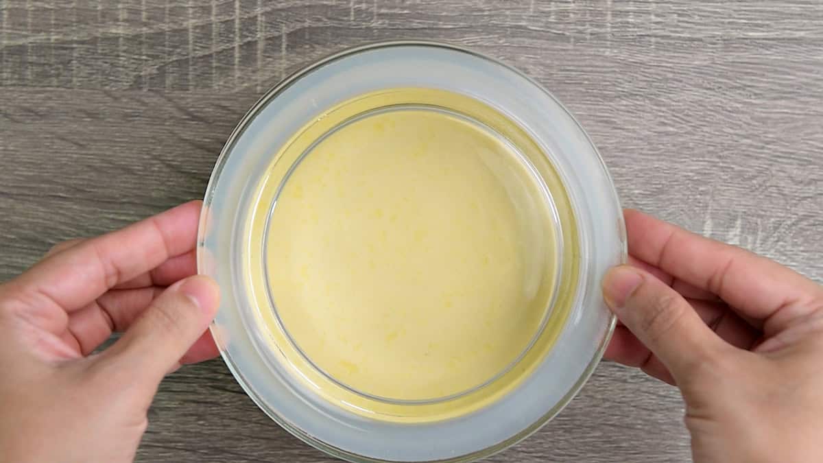 Top-down view of a sour cream jar being covered with glass lid to place in the refrigerator to chill.