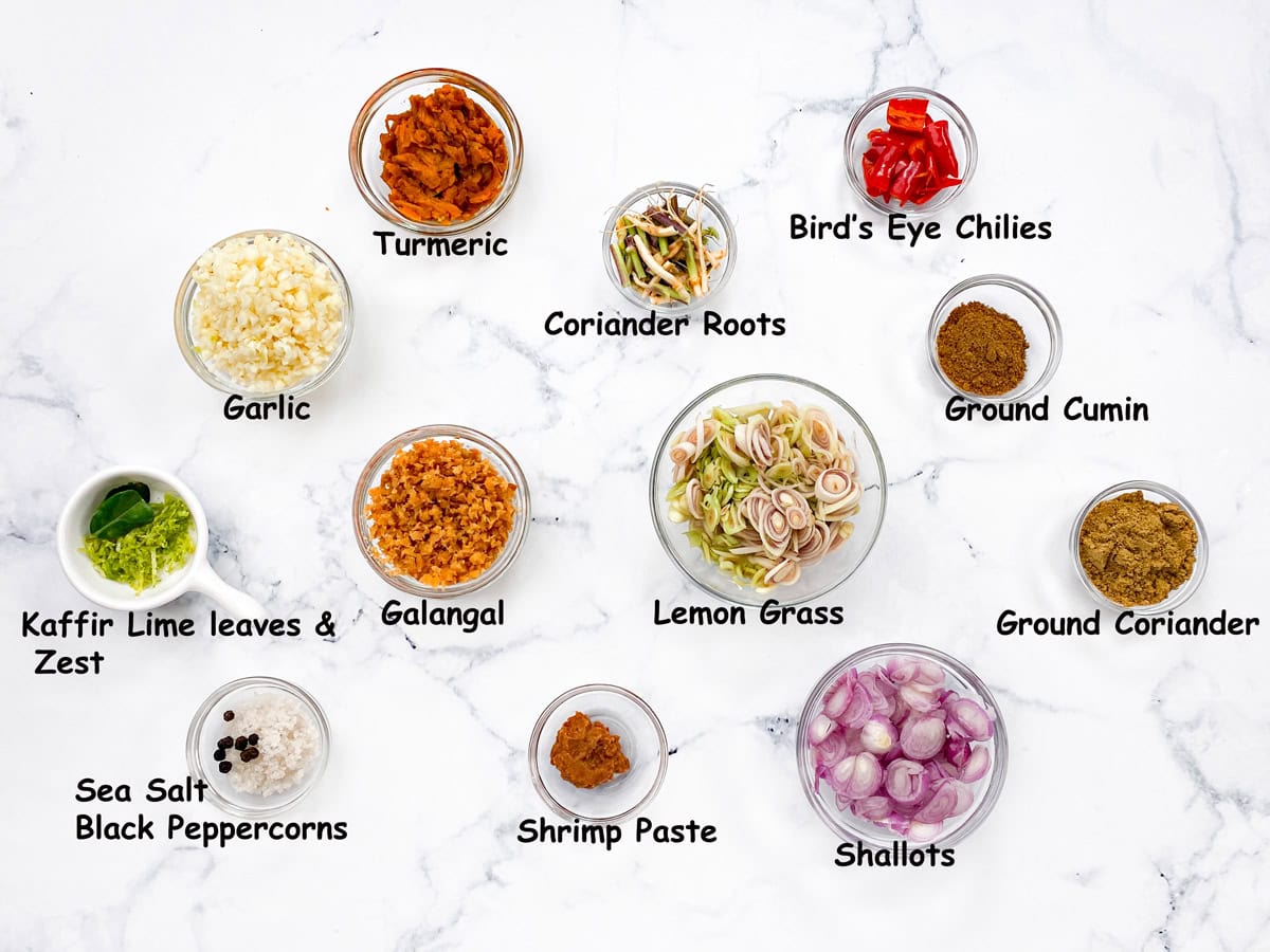 Top-down view of yellow curry paste ingredients in small glass bowls.