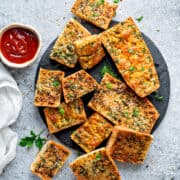 Top-down view of air fryer garlic bread on a plate topped with parsley and shredded parmesan.