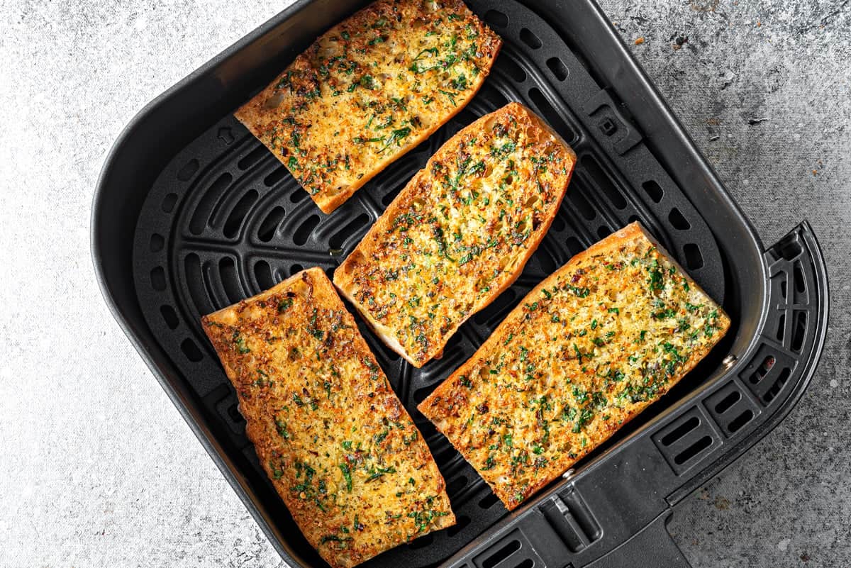 Top-down view of air-fried garlic bread inside the air fryer, cooked and ready to be served.