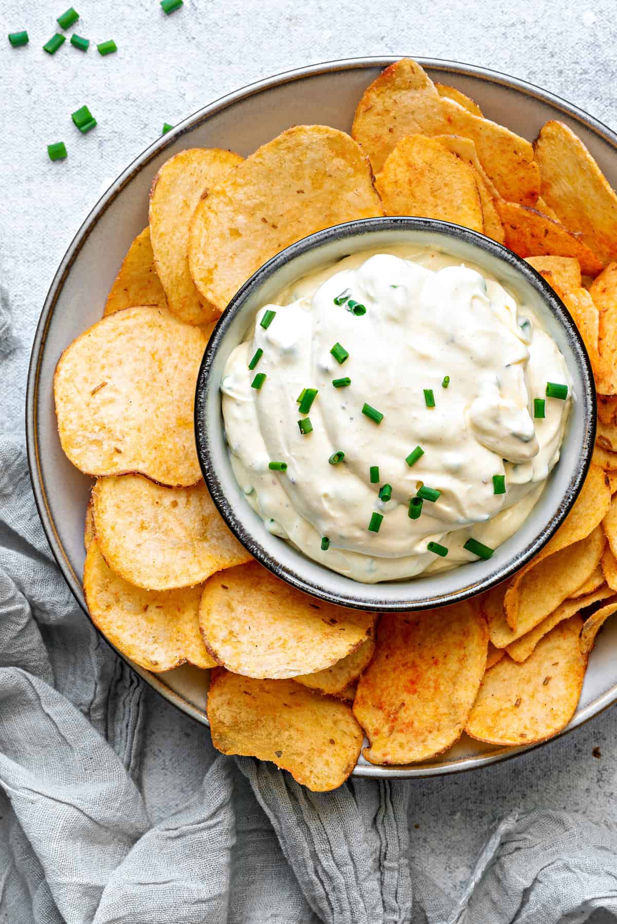Top-down view of serving platter with creamy sour cream dip and chips in a bowl.