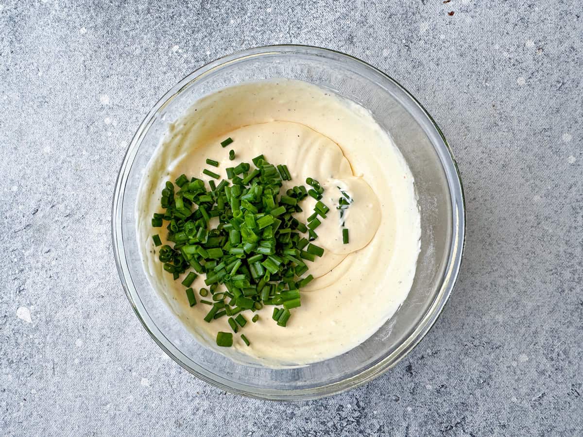 Top-down view of creamy dip with ingredients mixed inside a bowl and now with chives added to the mix.