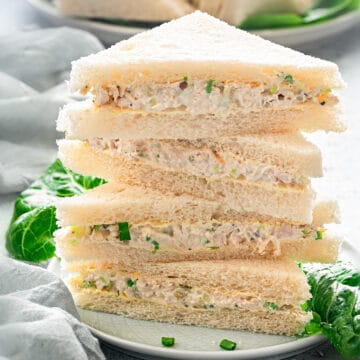 Close-up of a stack of chicken sandwich slices in triangle cuts on a plate, ready to be served.