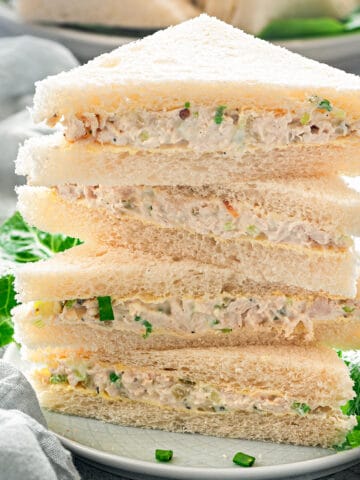Close-up of a stack of chicken sandwich slices in triangle cuts on a plate, ready to be served.