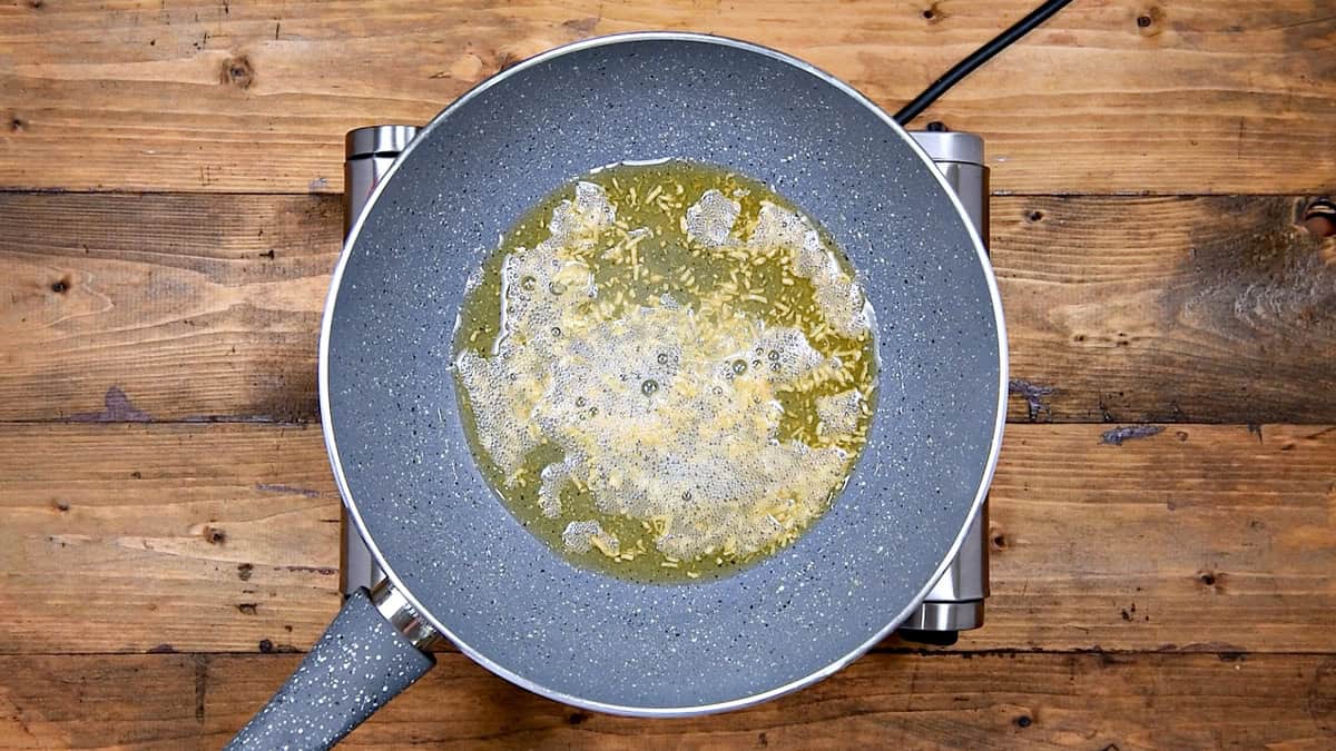 Sesame oil is heated in a wok with freshly grated garlic, sizzling for the preparation of spring roll filling.
