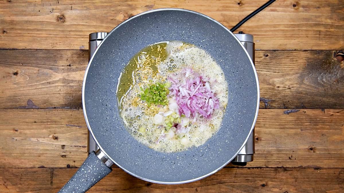 Chopped scallions white, red onion, and green chilies added to the wok.
