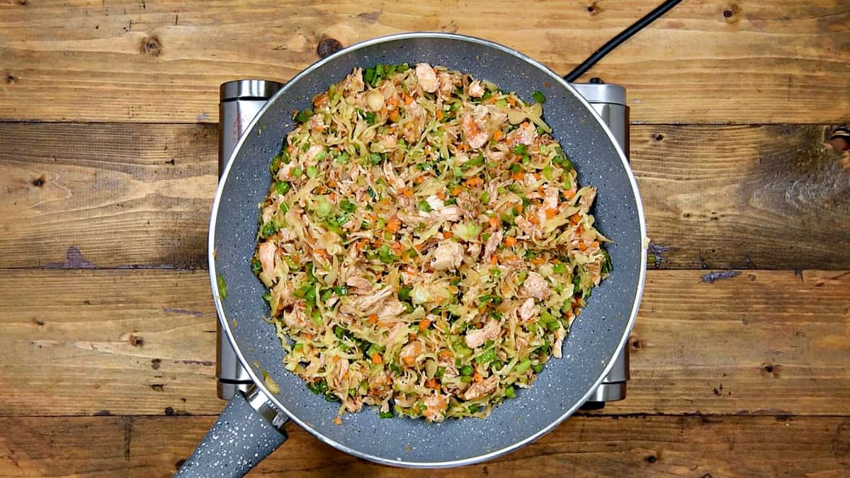Top-down view of cooling filling for the spring rolls in the wok.