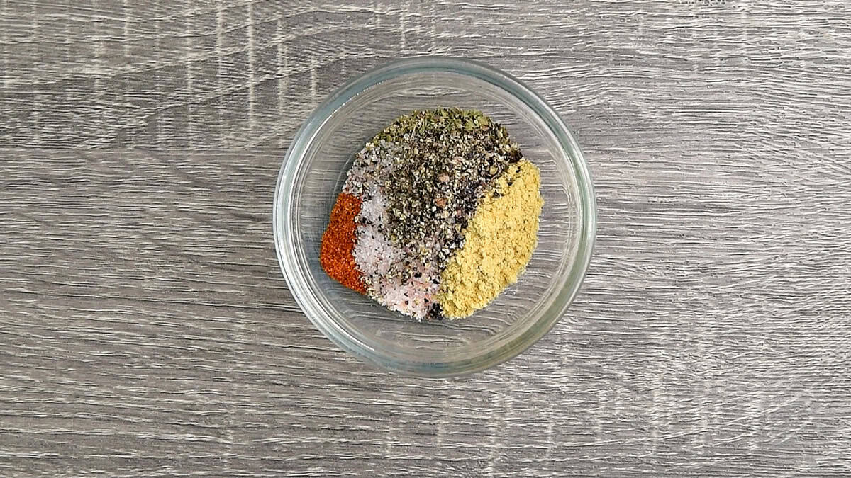 Seasonings like garlic powder, mustard powder, dried thyme, cayenne, salt, and ground pepper added to a small glass bowl.