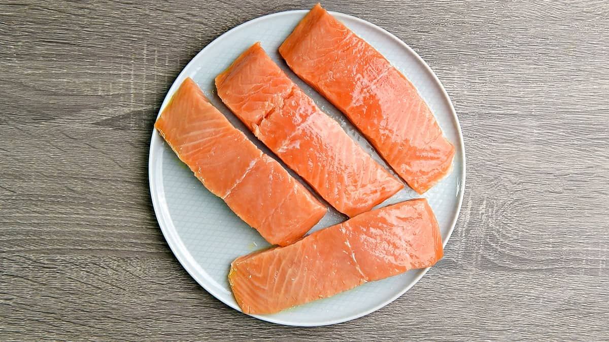 A top-down view of salmon fillets dried and then coated with olive oil on a plate.