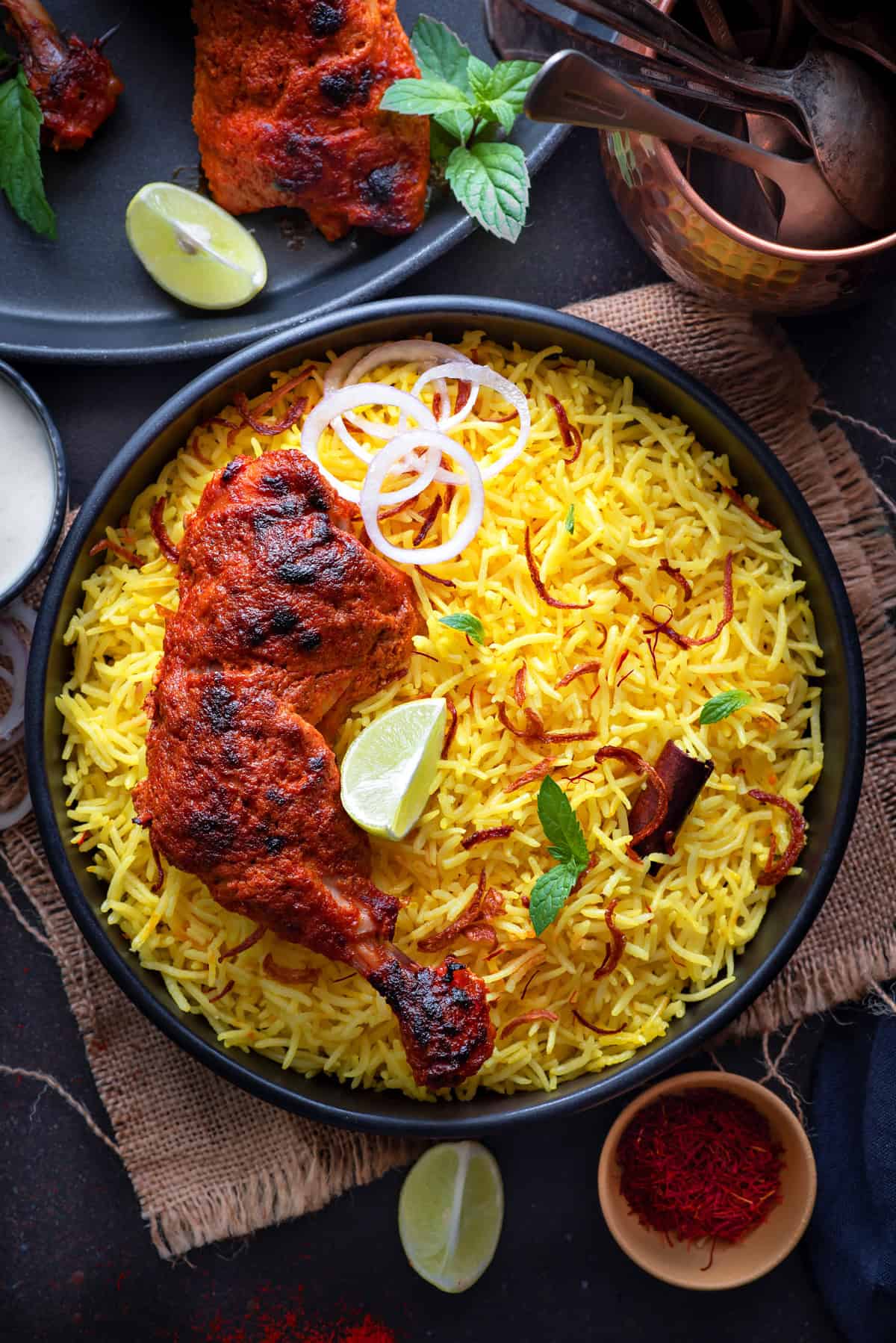 Top-down view of Middle Eastern saffron rice topped with onion slices, lime, cilantro, and chicken ready to be served.